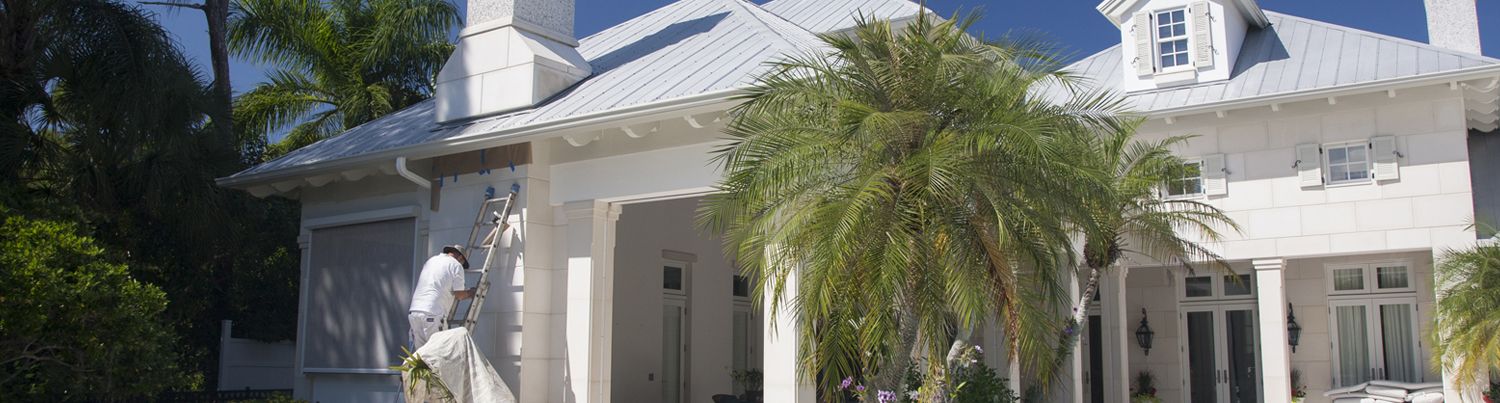 Painter on ladder outside home being painted by Pelican Painting Company in Sarasota 
